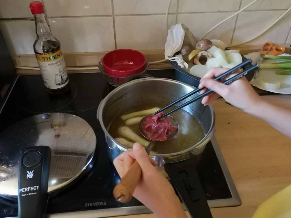 Normalerweise gart das Fleisch im letzten Moment auf dem Teller, wenn die kochend heiße Pho-Brühe darüber gegossen wird. Man kann aber etwas dick geratete Stücke auch vorher schon mal kurz in die Brühe tunken. Foto: Heiko Weckbrodt