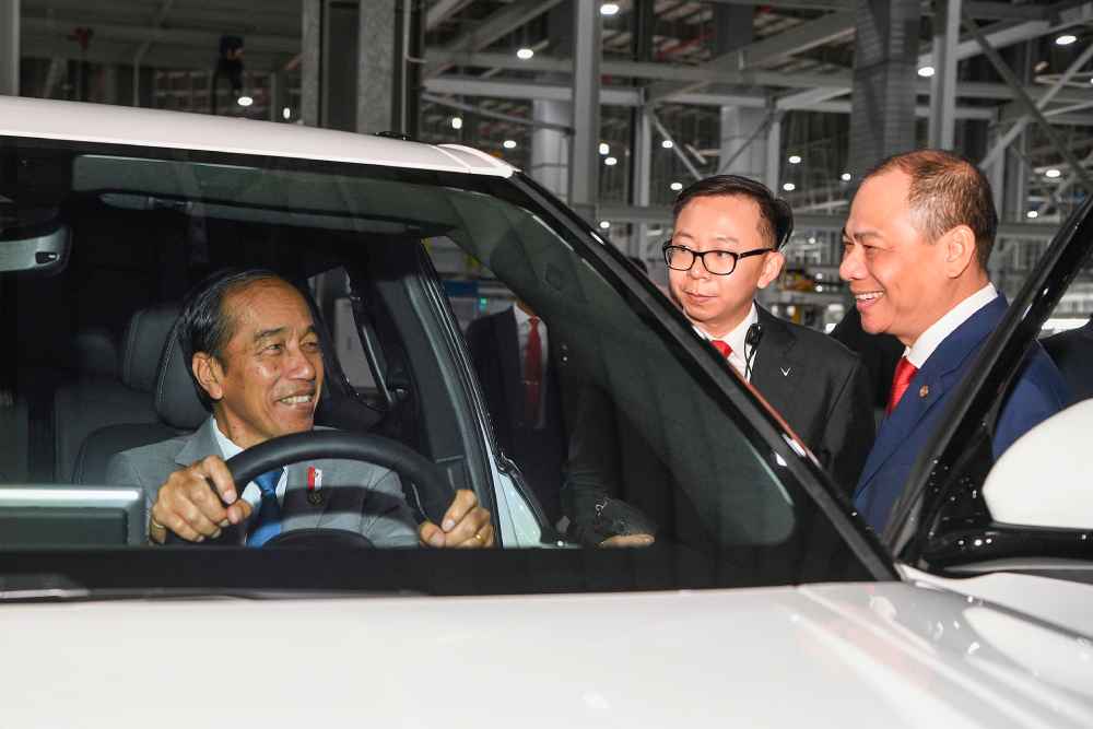 Der indonesische Präsident Joko Widodo probiert im vietnamesischen Autowerk Haiphong einen Vinfast-Stromer aus, eskortiert von Vingroup-Konzernchef Pham Nhat Vuong (rechts). Foto: Vinfast